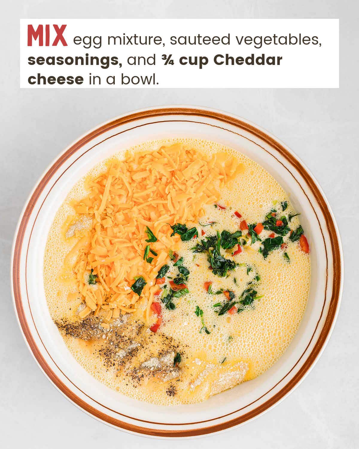 Eggs mixed with Cheddar cheese, chopped vegetables, and seasonings in a bowl.