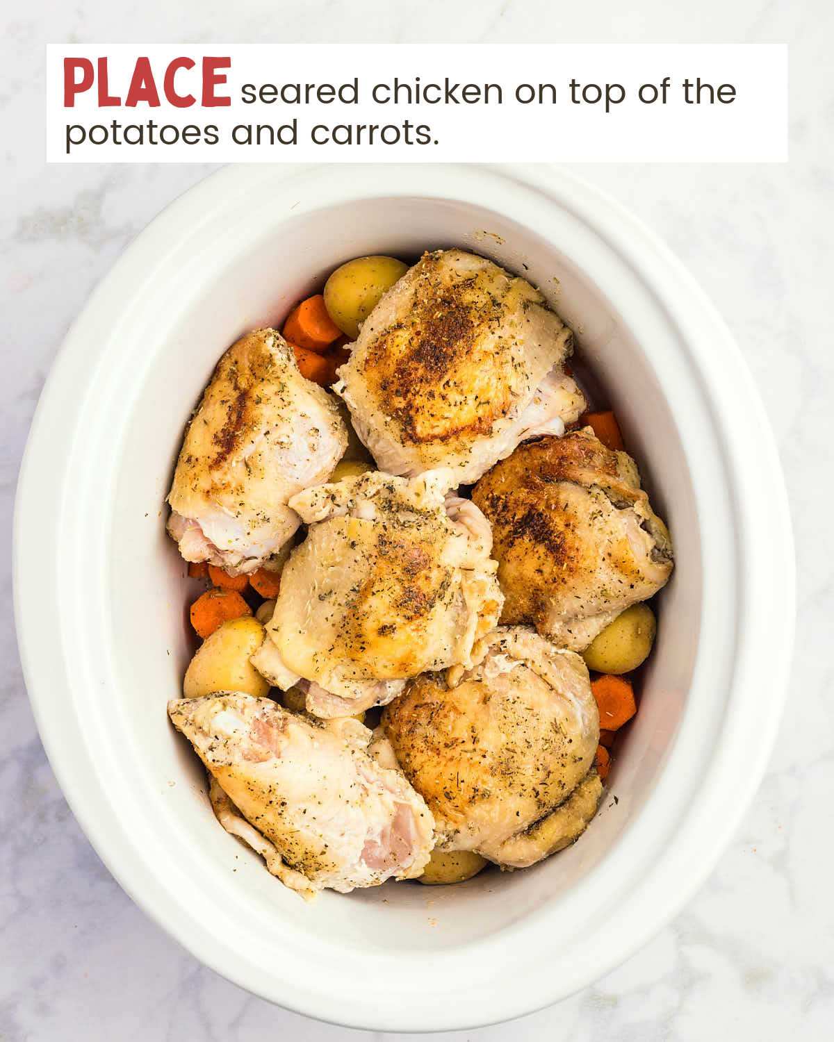 Seared chicken thighs over potatoes and chopped carrots in a slow cooker.