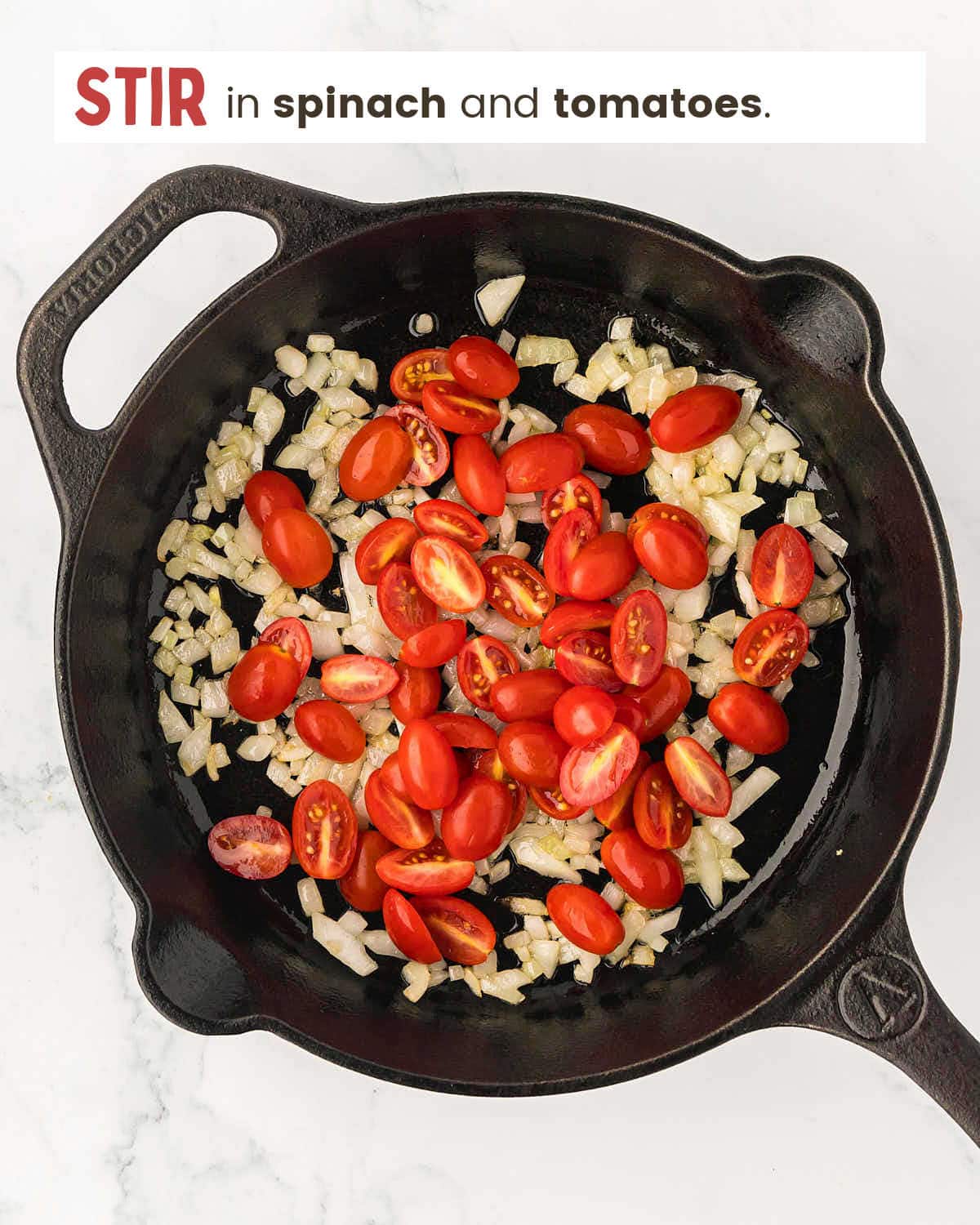 Chopped onions and cherry tomatoes in a cast iron pan.