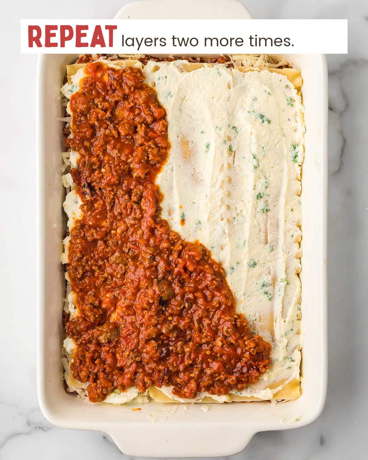 Partial meat sauce layer with ricotta layer of lasagna in a baking dish.