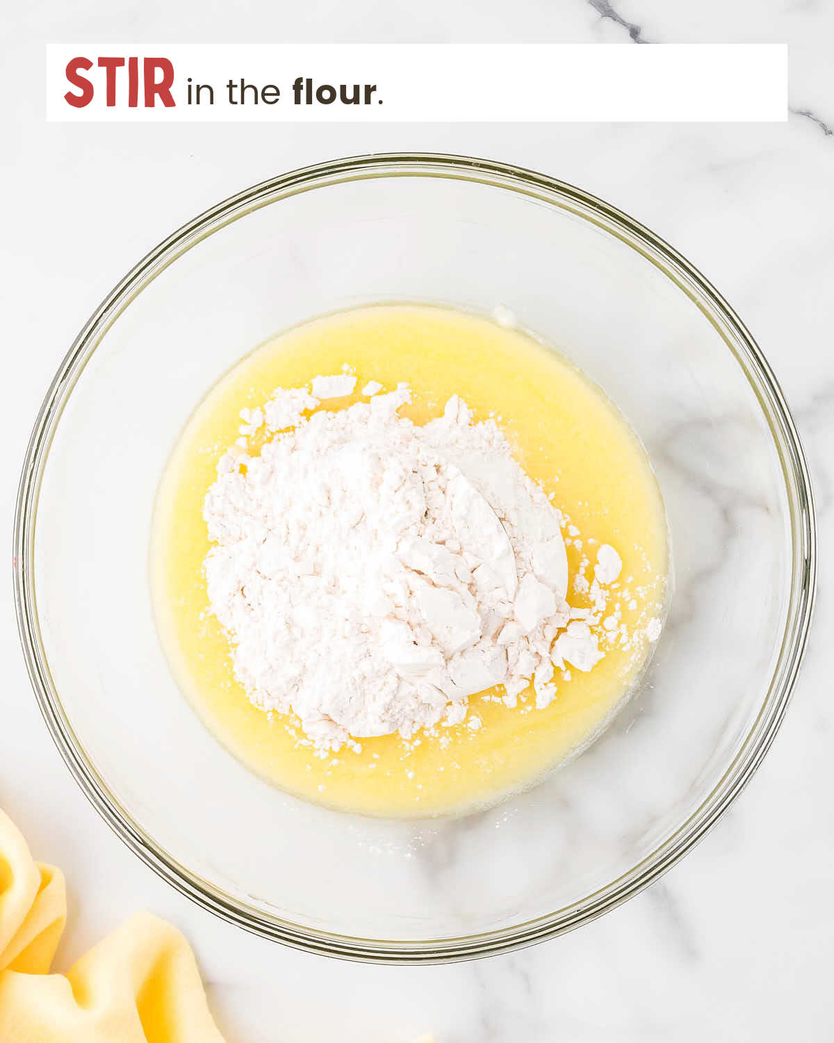Melted butter, sugar, and salt mixed in a bowl with flour on top.