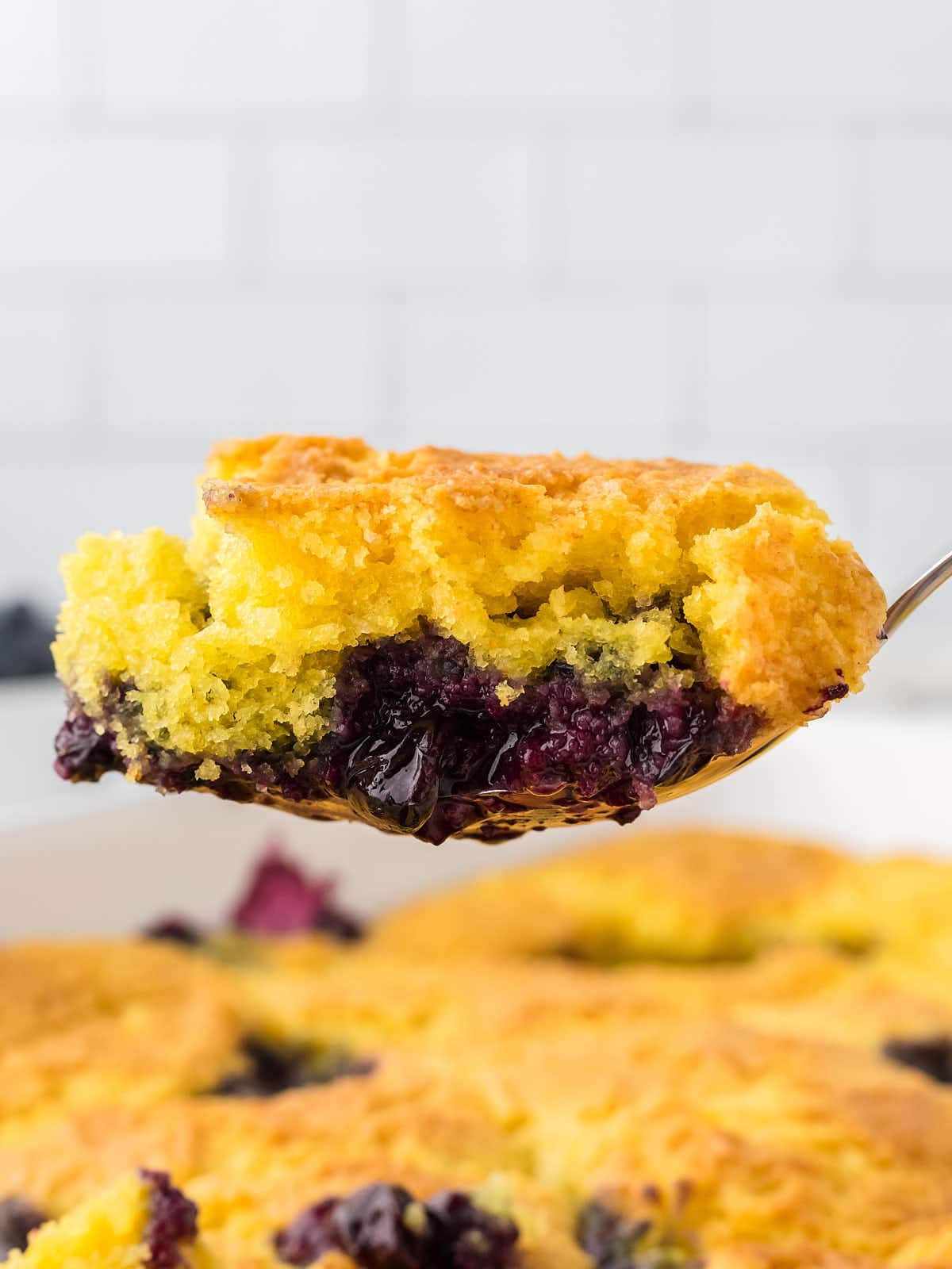 A serving spoon filled with Lemon Blueberry Dump Cake.