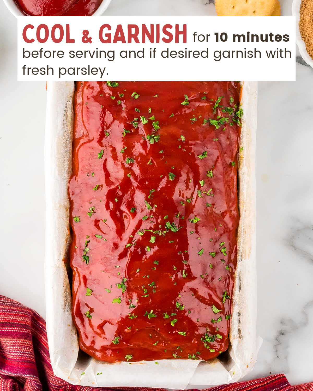 Sauce covers meatloaf in a parchment lined loaf pan.