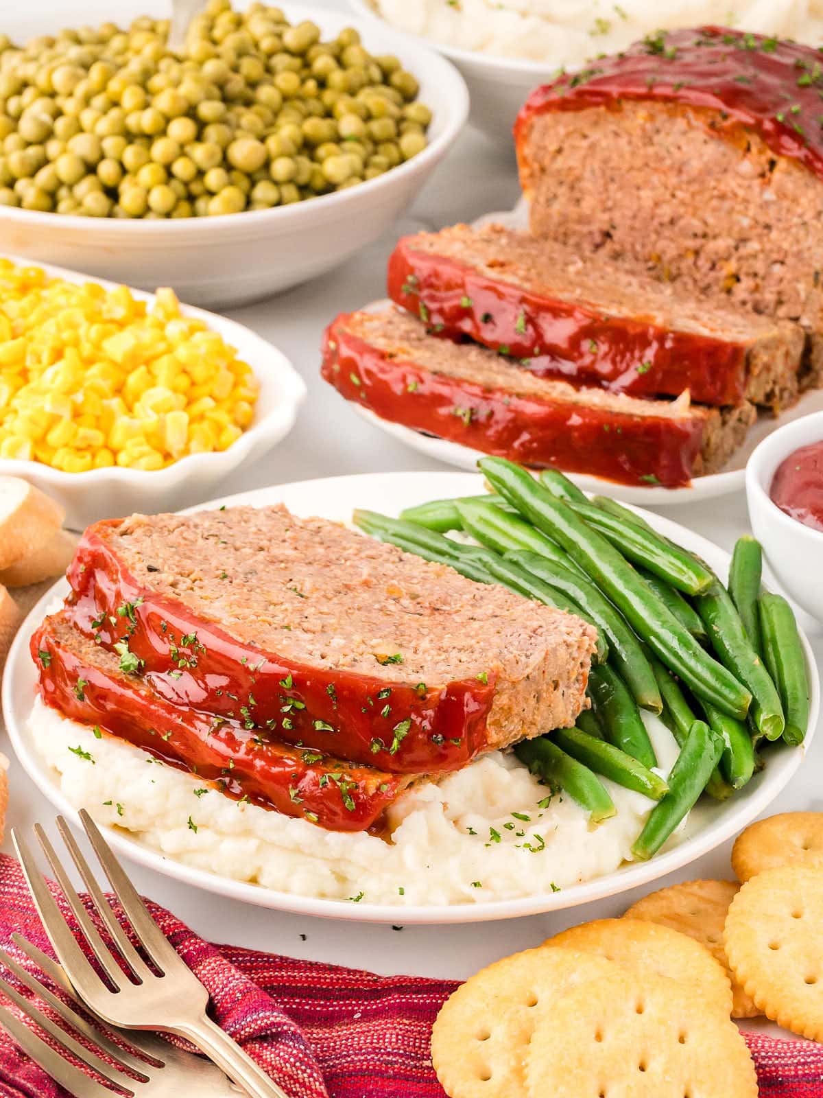 Two slices of Meatloaf served on mashed potatoes with green beans.
