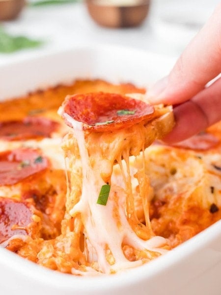 Scooping out a Pizza Dip with slice of baguette.