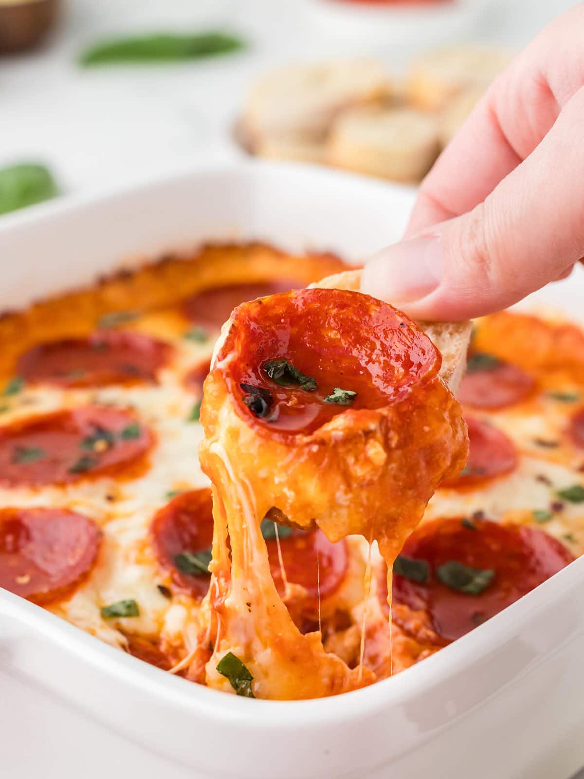 Side shot of scooping cheesy Pizza Dip out of the baking dish.