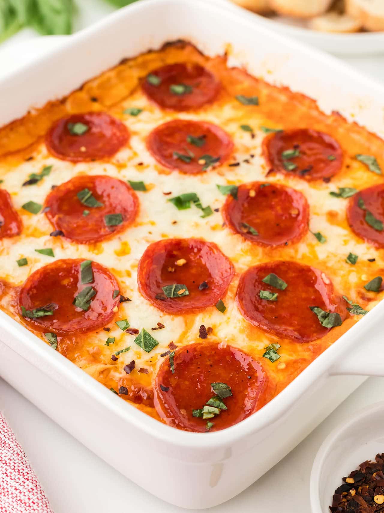 Side angle view of the Pizza Dip in a white baking dish.