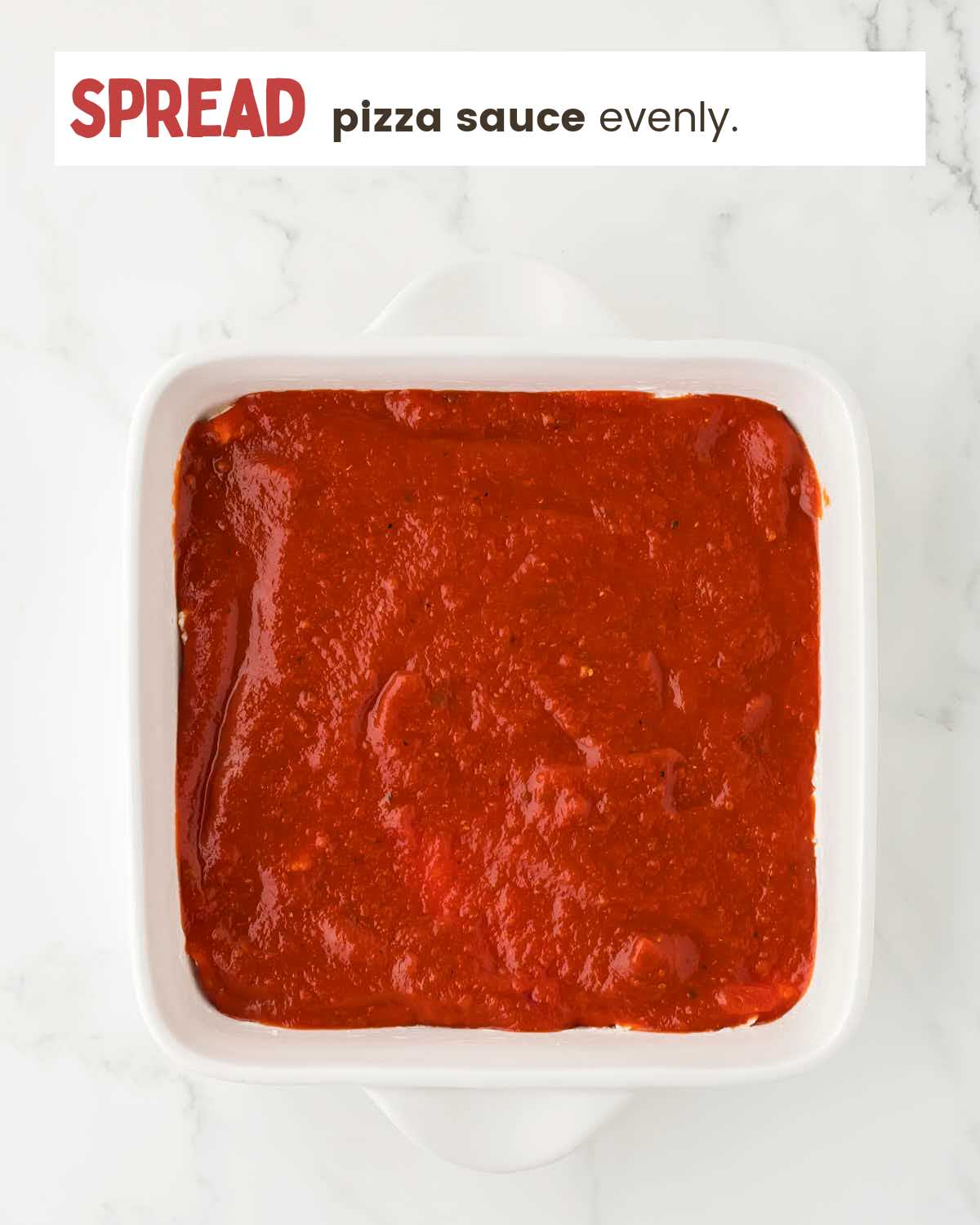 Cream cheese mixture topped with pizza sauce in a dish.