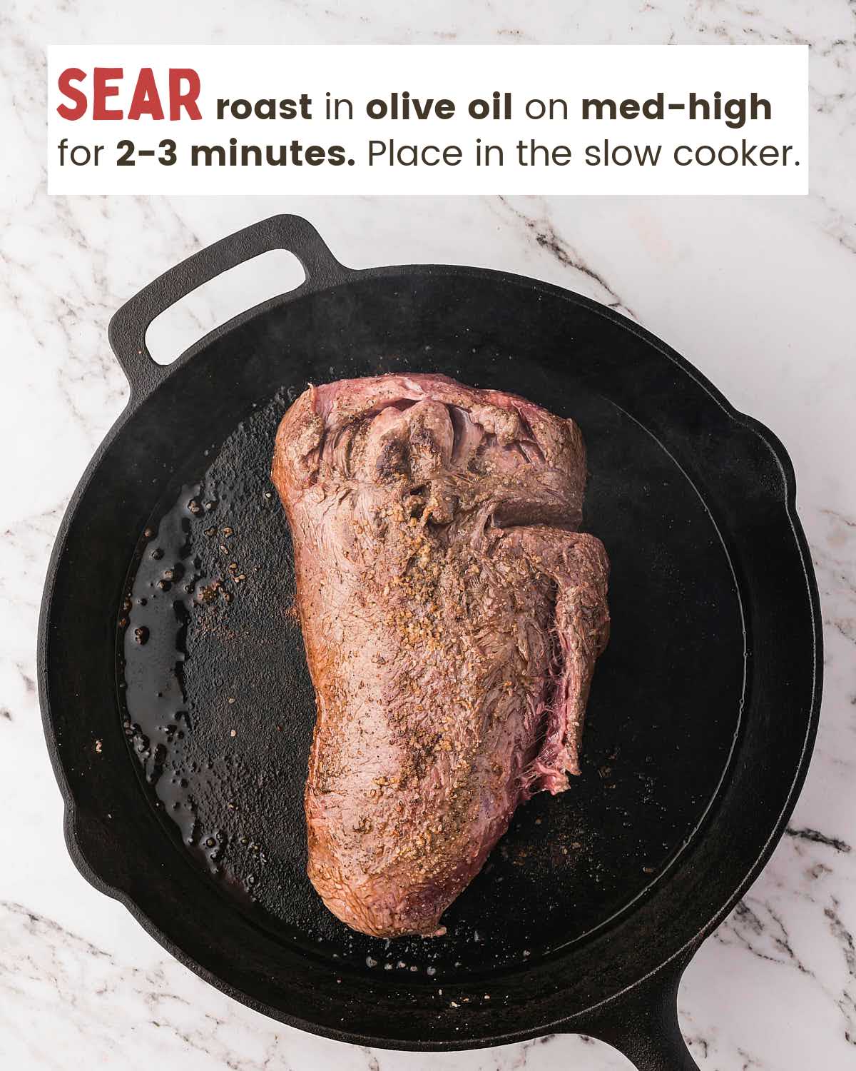 Seared chuck roast in a cast iron skillet with olive oil.