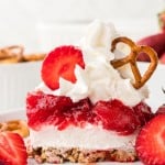 A slice of Strawberry Pretzel Salad topped with whipped cream on a white plate.