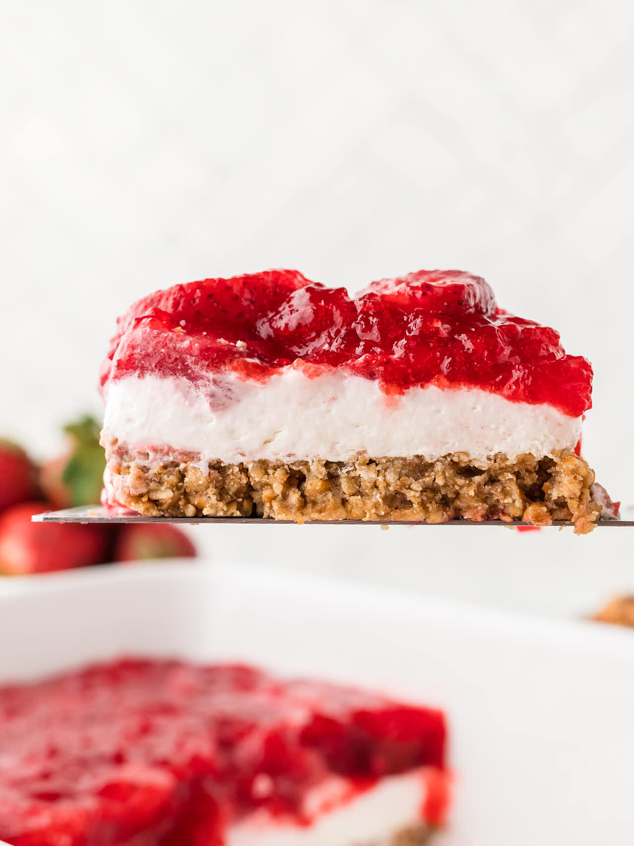 Lifting a slice of Strawberry Pretzel Salad out of the baking dish.