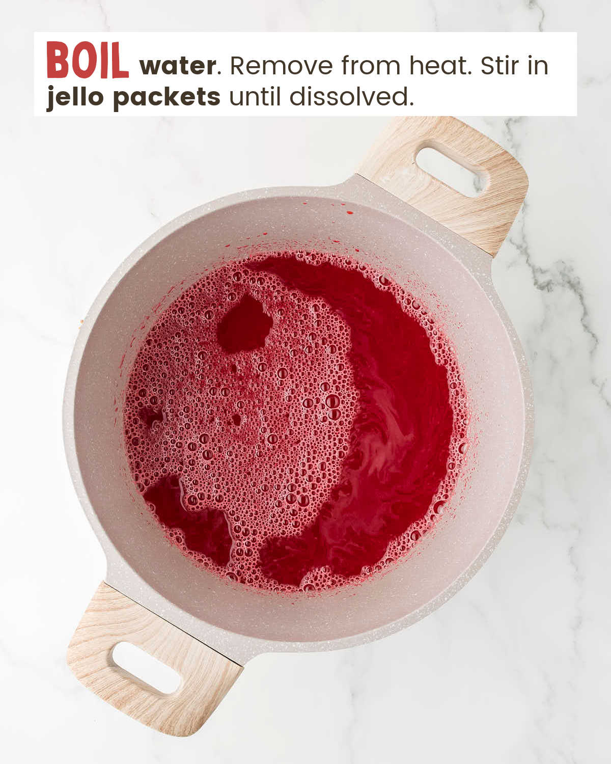 Water with dissolved strawberry Jello packets in a pot.
