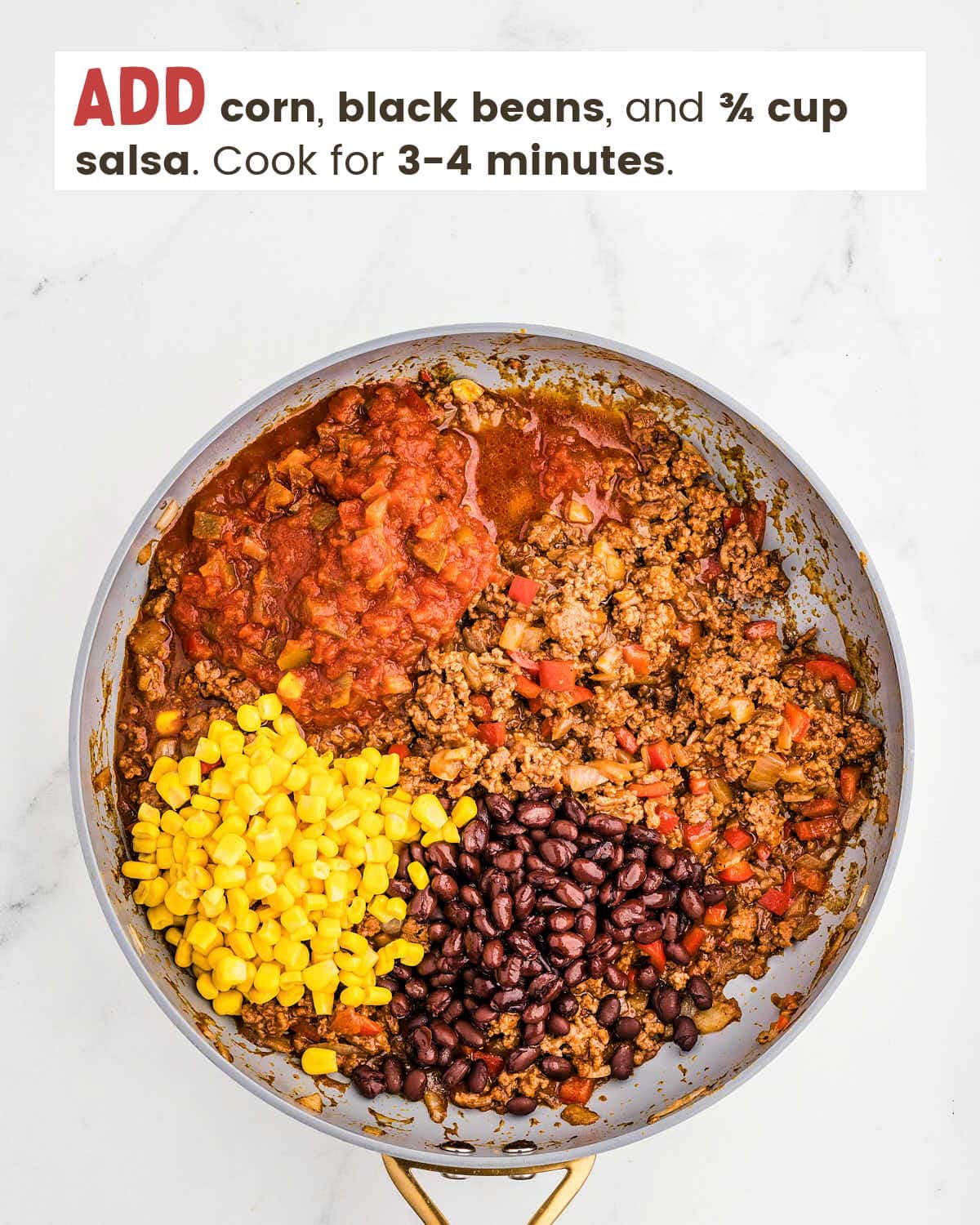 Ground beef mixture topped with corn, black beans, and salsa in a skillet.