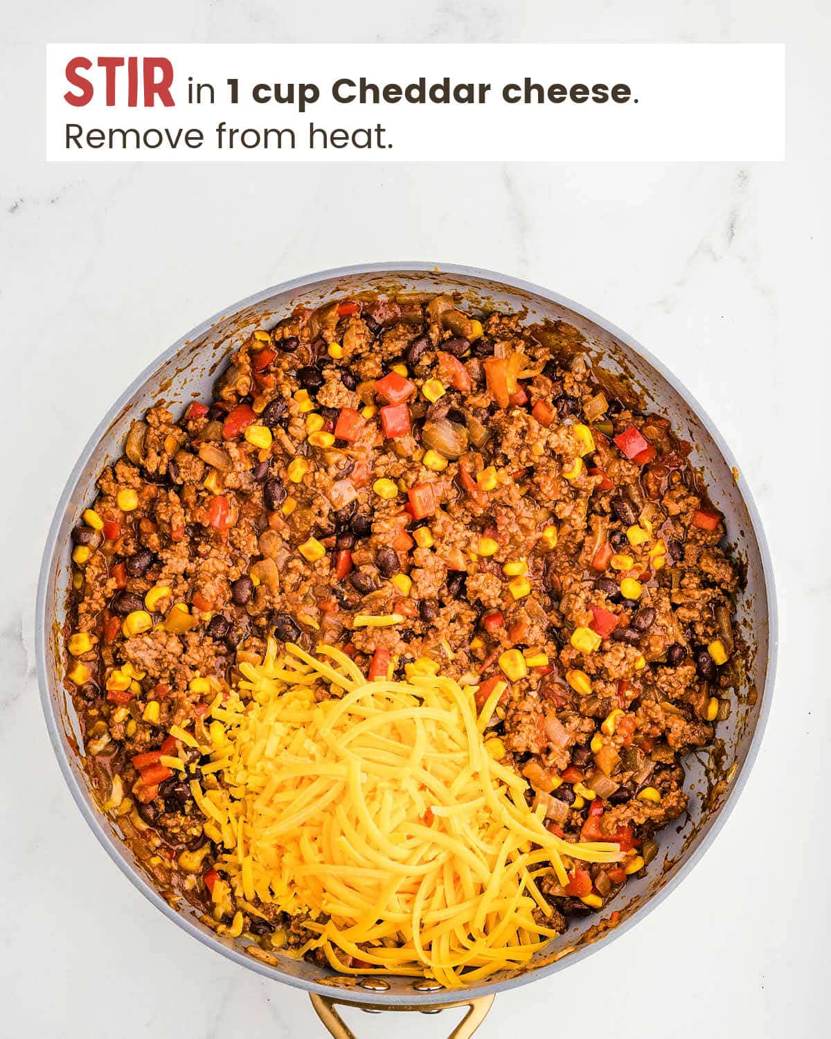 Ground beef mixture topped with Cheddar cheese in a skillet.
