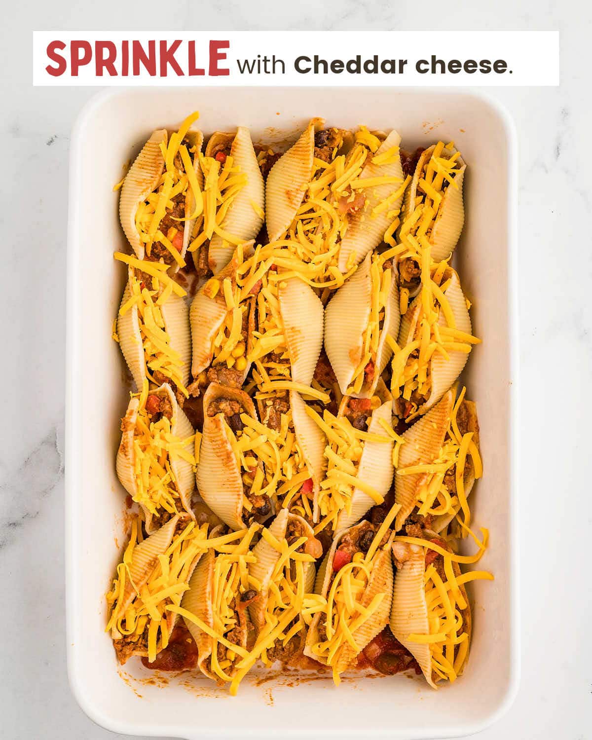 Stuffed pasta shells topped with cheese in a baking dish.