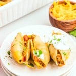 Three cheesy Taco Stuffed Shells on a white plate.