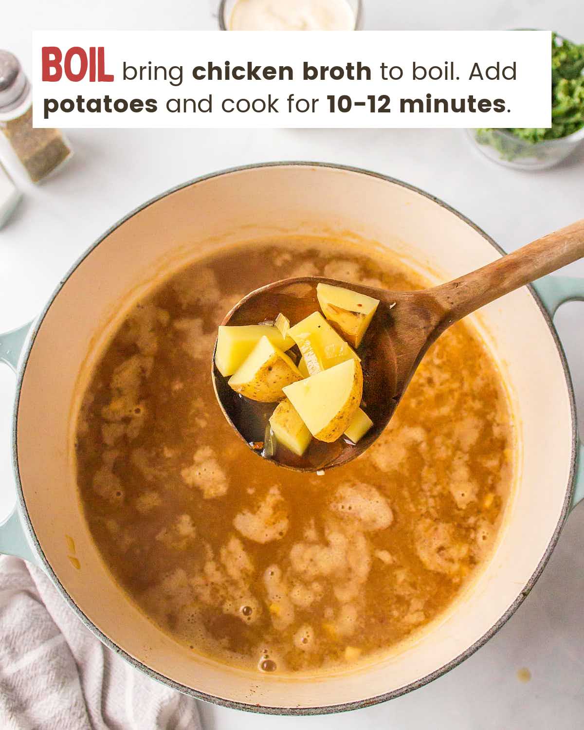 A spoon with chopped potatoes over a pot filled with chicken broth.