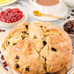 A loaf of Irish Soda bread with tea, butter, and jam.