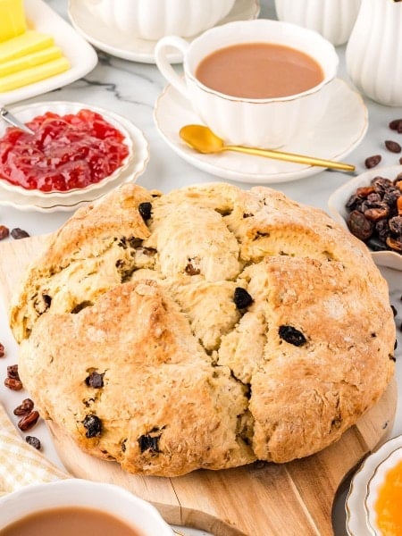 A loaf of Irish Soda bread with tea, butter, and jam.