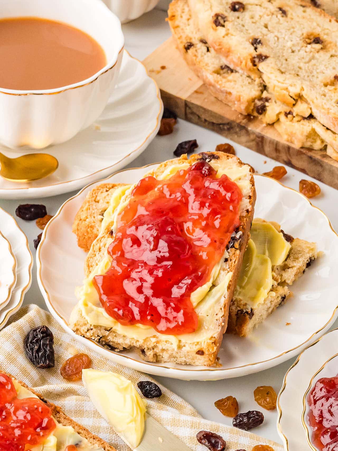 Slices of Irish Soda Bread with butter and jam served on a white plate.
