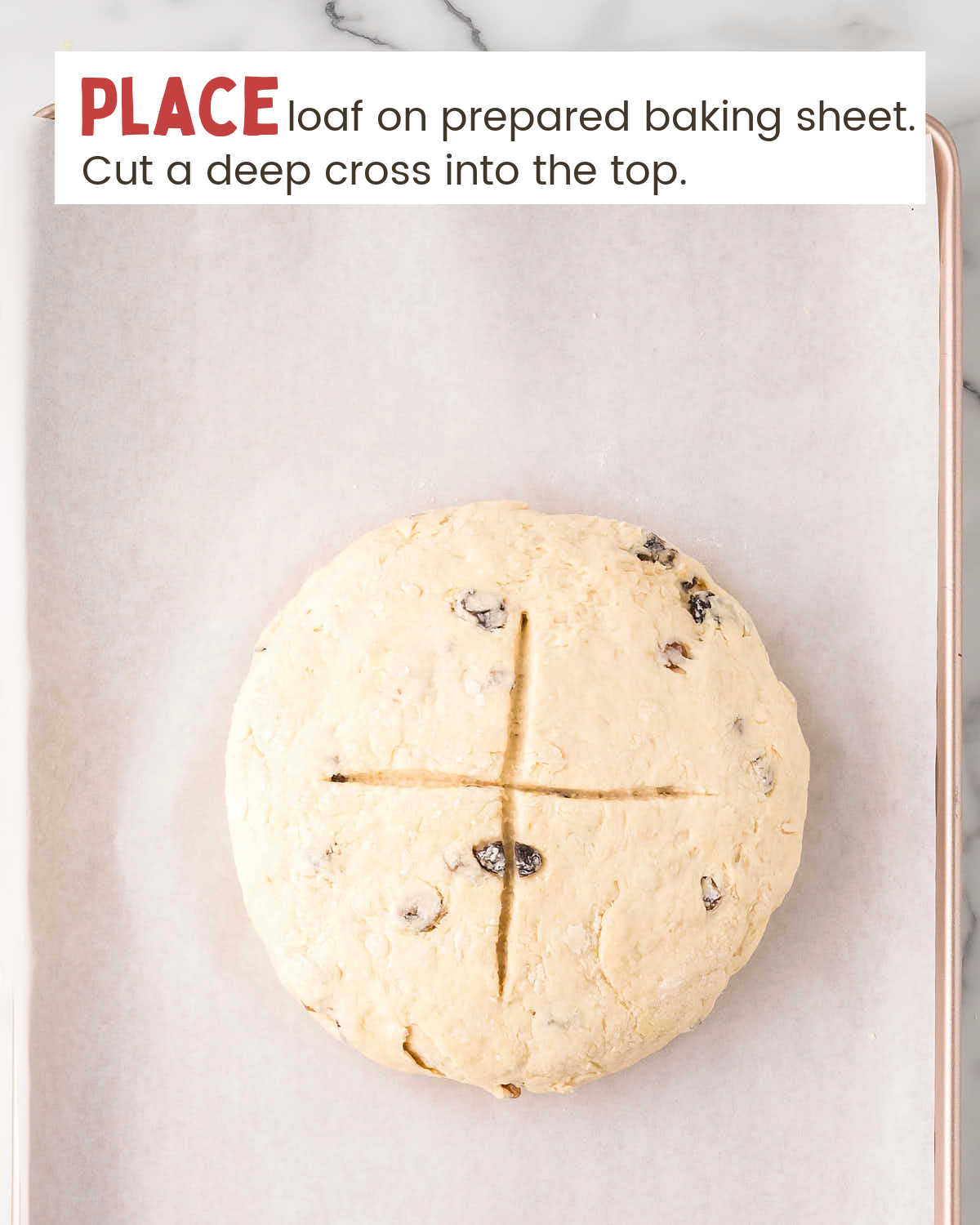 Irish soda bread dough with an X cut into the top on a parchment-lined baking sheet.