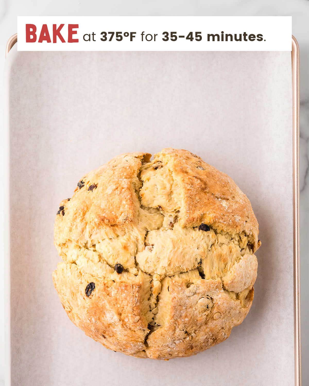 Baked Irish soda bread dough on a parchment-lined baking sheet.