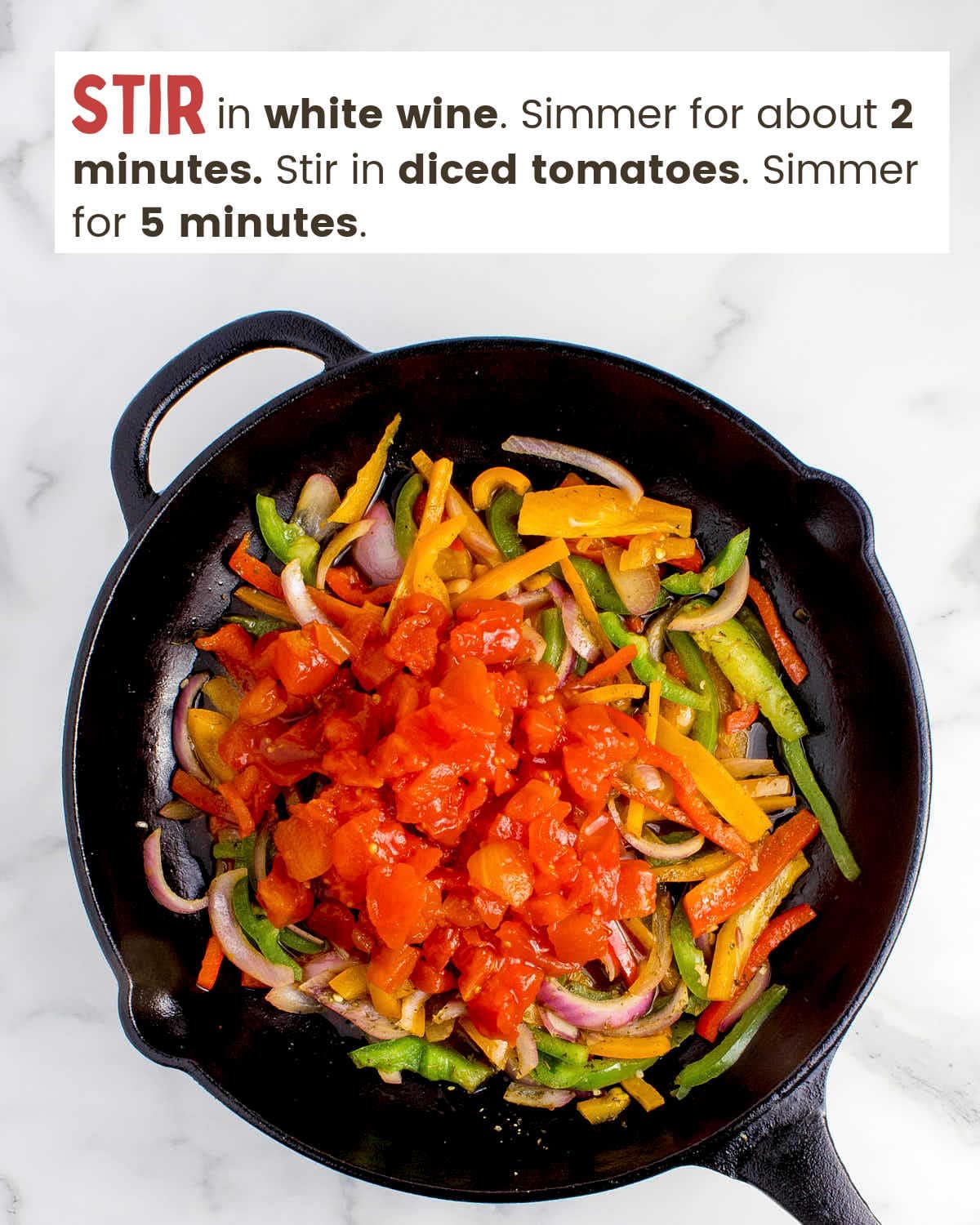 Sliced bell peppers and onions topped with diced tomatoes in a cast iron skillet.