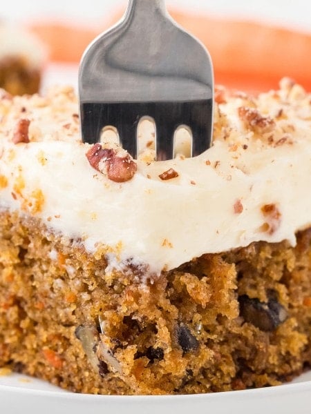 A fork digging into a slice of Carrot Cake.