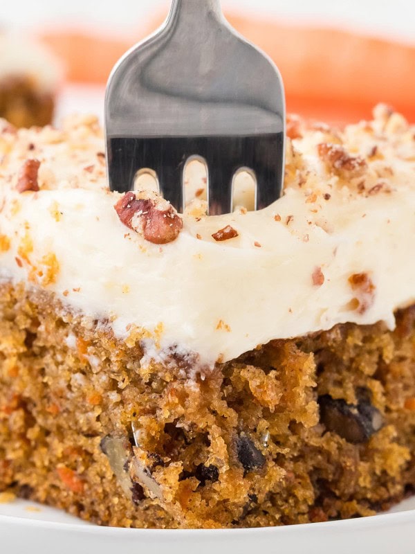 A fork digging into a slice of Carrot Cake.