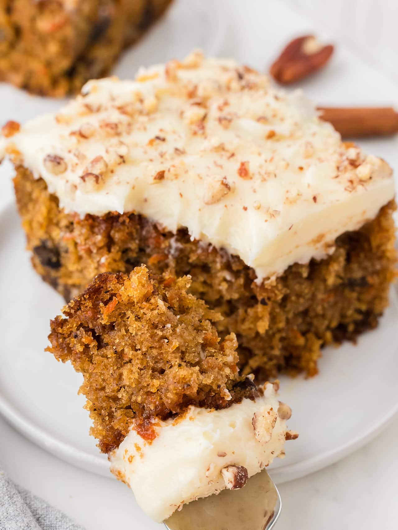 Carrot Cake with a fork served on a white plate.