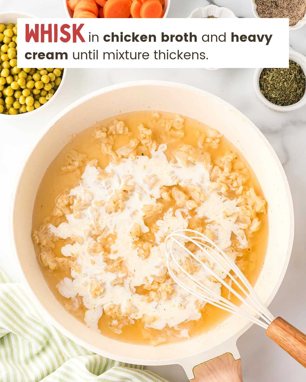 A whisk in a pan with chicken broth and heavy cream over an onion and garlic mixture.