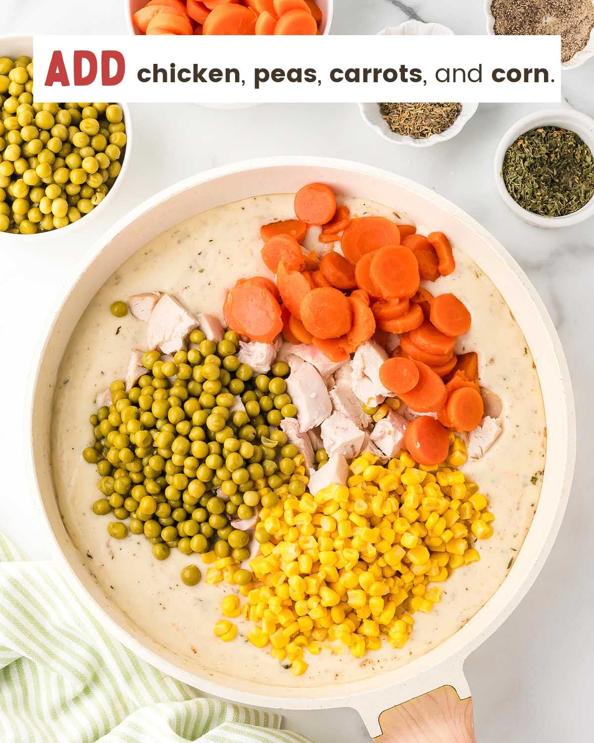 Chicken pieces, peas, carrots, and corn on top of a chicken pot pie filling heavy cream mixture.