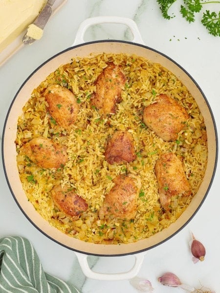 Topdown view of cooked Chicken Thighs and Rice in a white skillet.