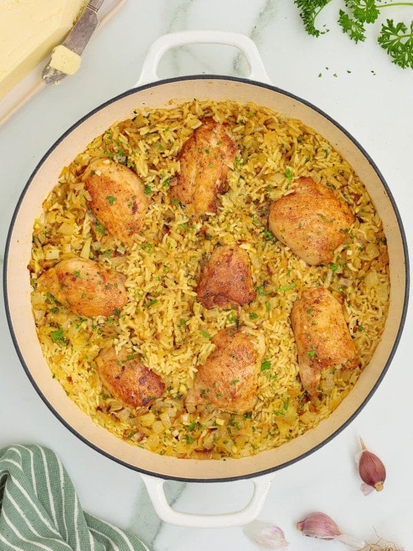 Topdown view of cooked Chicken Thighs and Rice in a white skillet.