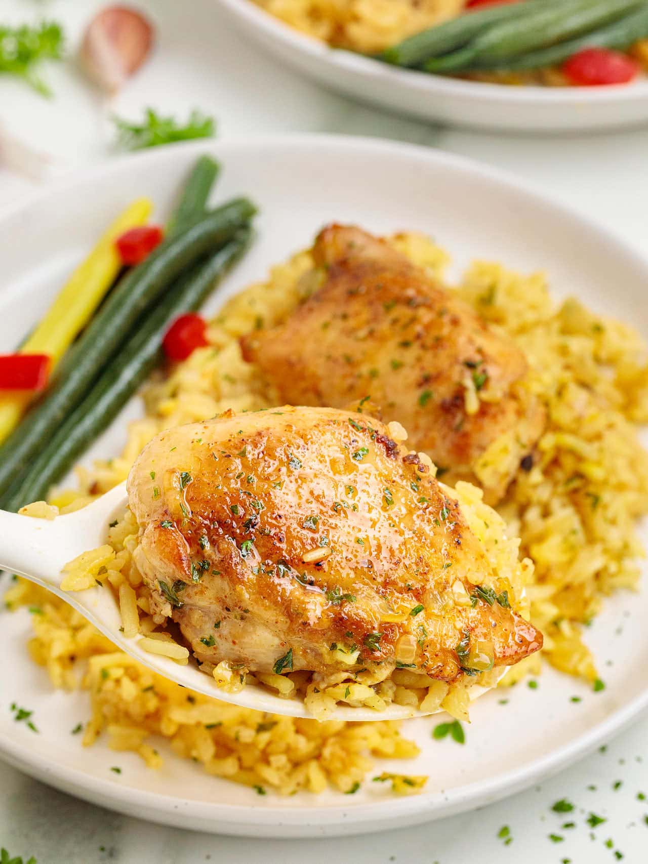 Chicken Thighs and Rice served on a white plate with beans and bell peppers.