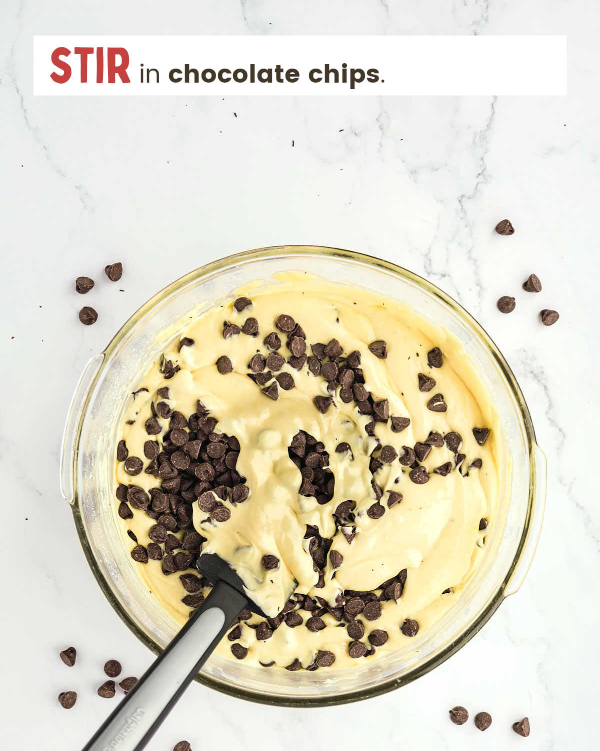 Chocolate chips being stirred into cake batter with a spatula.