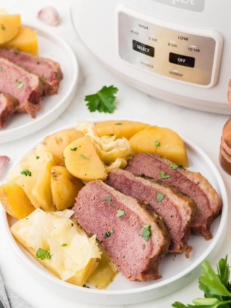 A Corned Beef and Cabbage with boiled potatoes on a white plate.