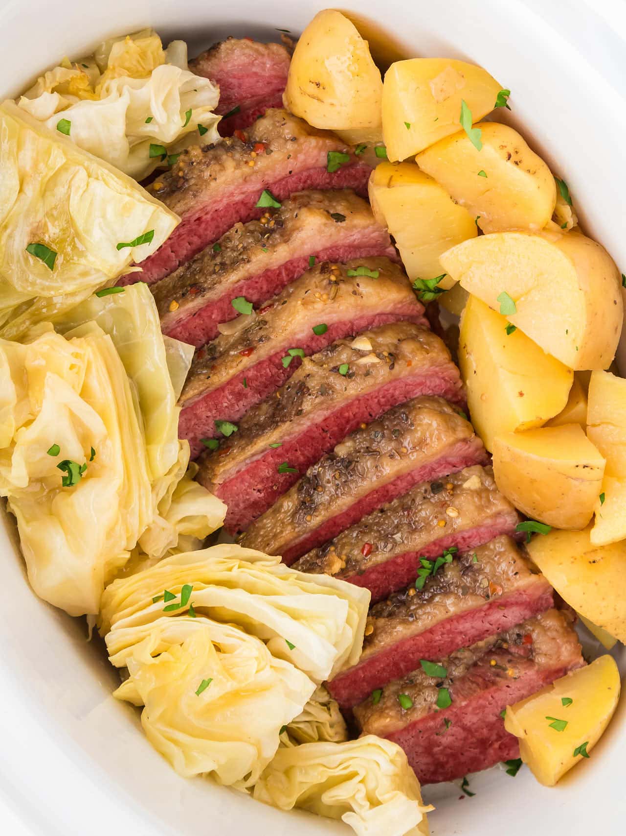 Corned Beef and Cabbage with potatoes in a white Crock Pot.