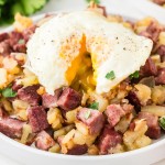 Corned Beef Hash on a white plate with an eggs over easy.