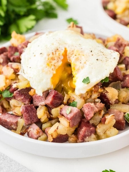 Corned Beef Hash on a white plate with an eggs over easy.