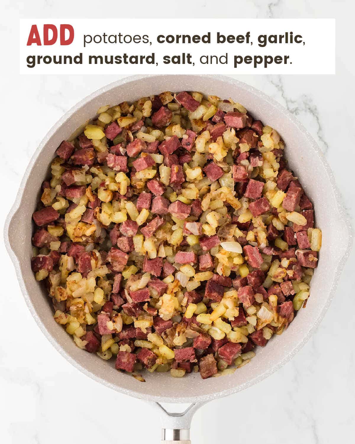Cooked potatoes, corned beef, and spices added to the white skillet.