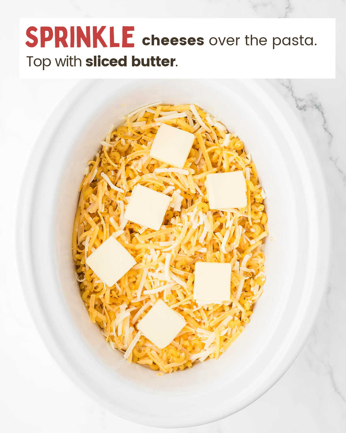 Butter slices on top of cheeses that cover macaroni in a crockpot.