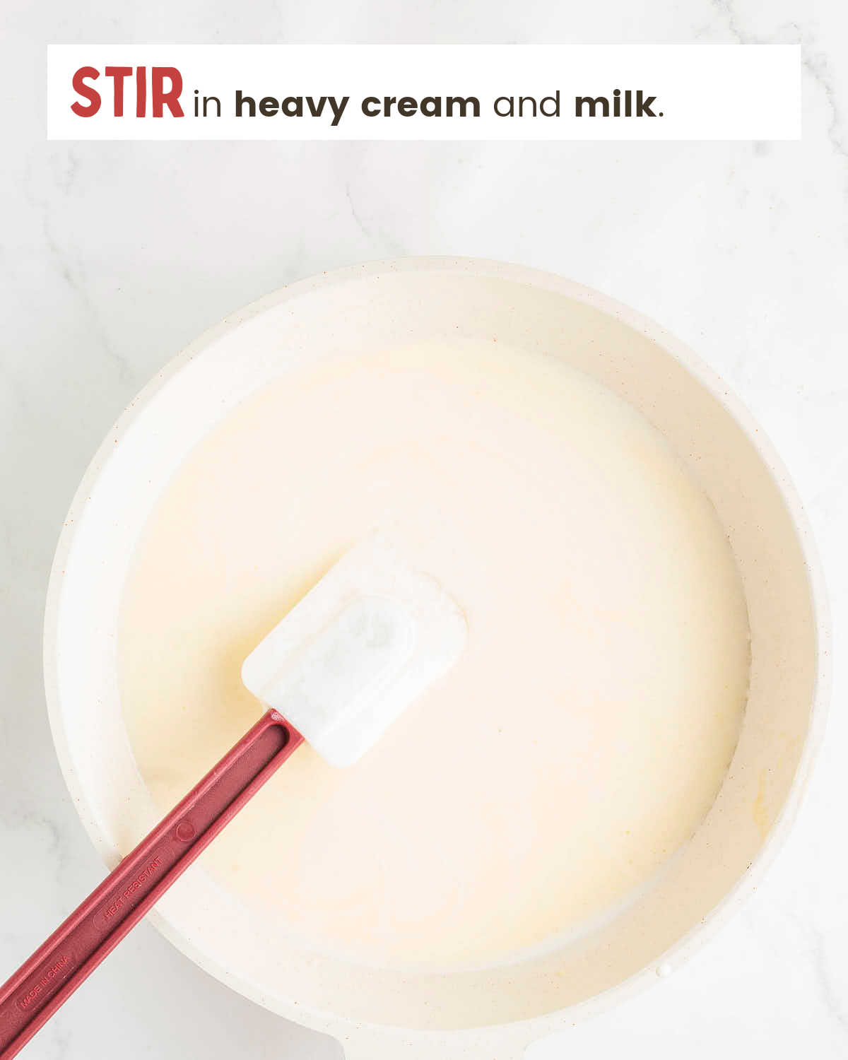 A spatula in milk and cream mixture in a skillet.