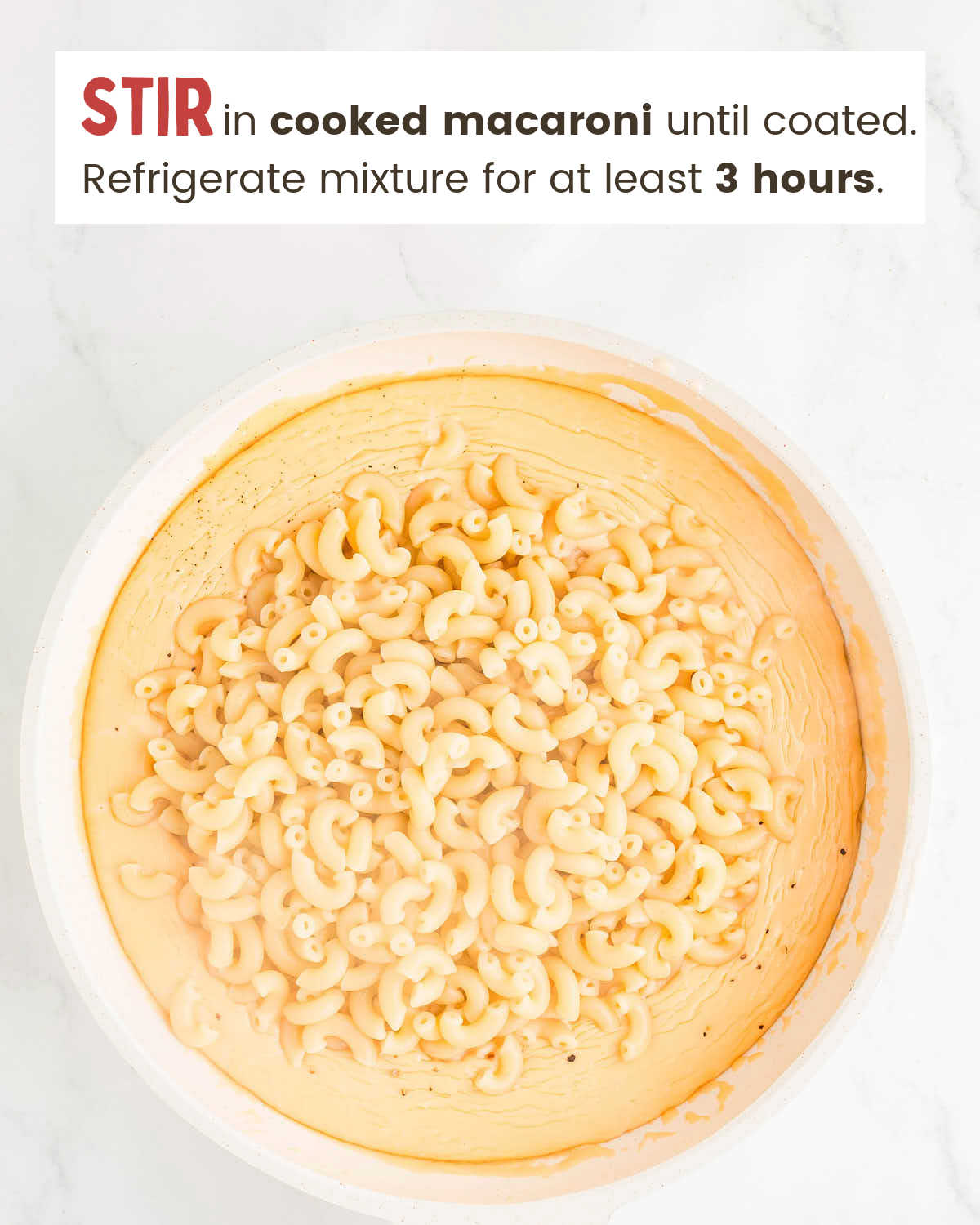 Cooked macaroni on top of a cheese mixture in a skillet.
