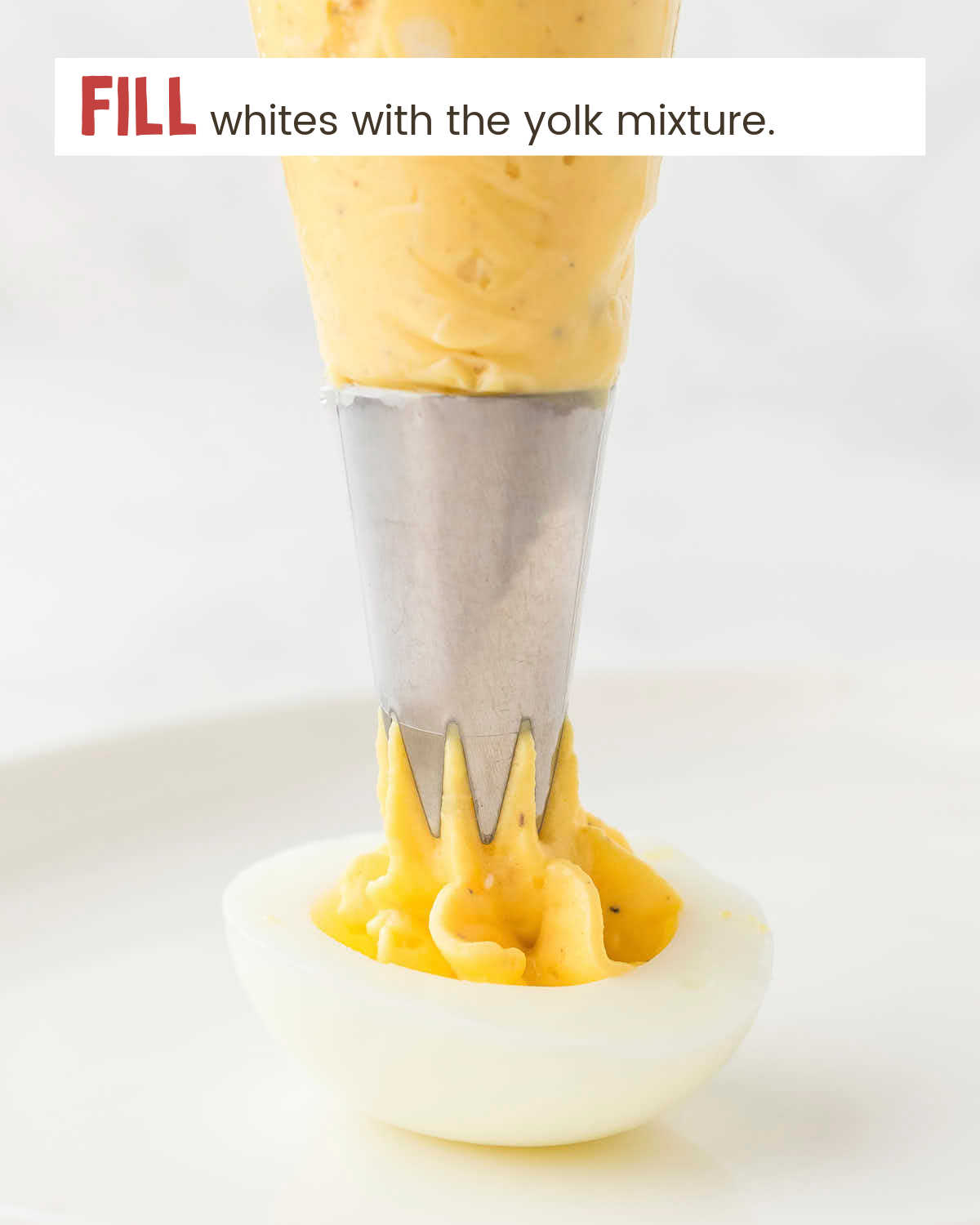 Egg yolk mixture in a piping bag filling a halved egg white.