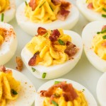 Closeup of several Million Dollar Deviled Eggs on a white plate.