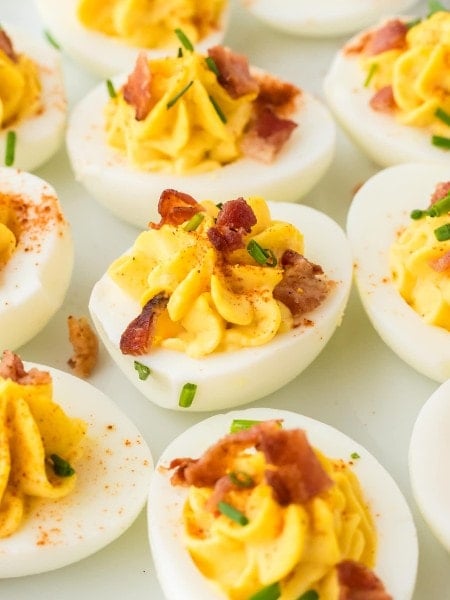 Closeup of several Million Dollar Deviled Eggs on a white plate.