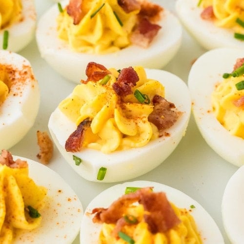 Closeup of several Million Dollar Deviled Eggs on a white plate.