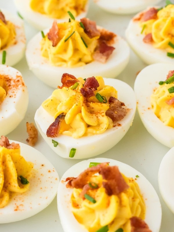 Closeup of several Million Dollar Deviled Eggs on a white plate.