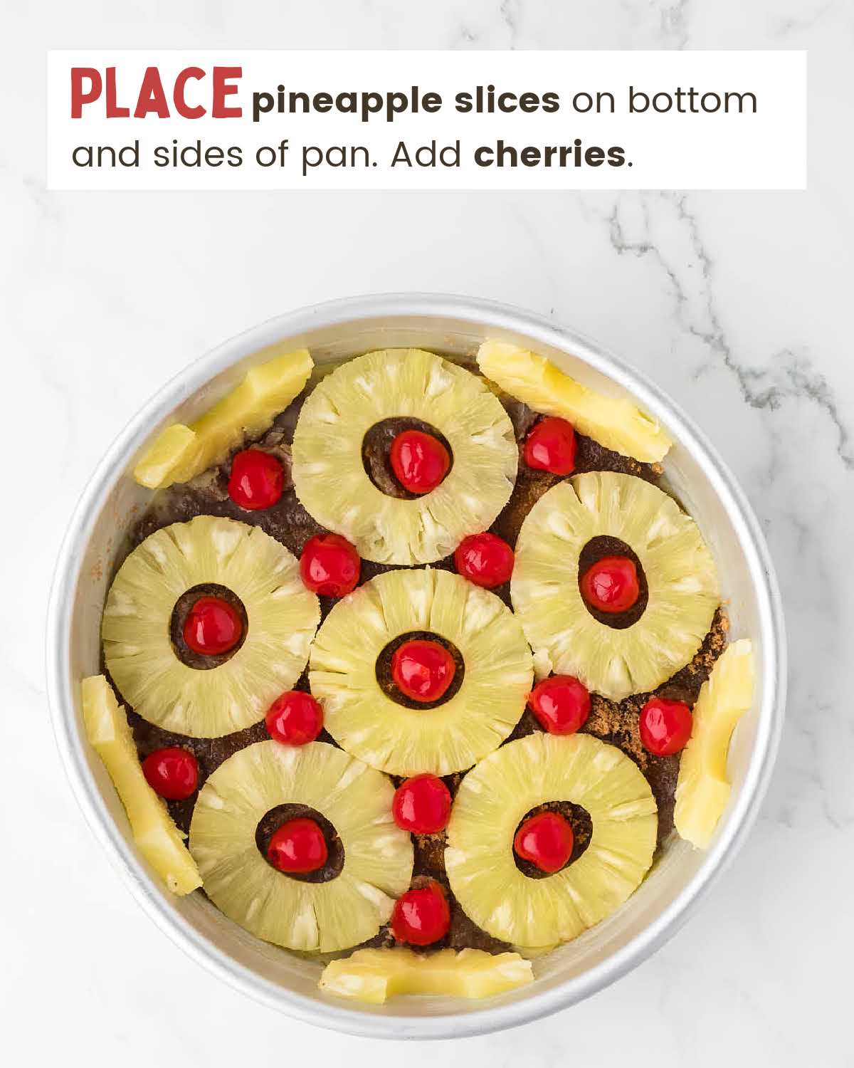 Pineapple slices and cherries in a cake pan on sides and bottom.